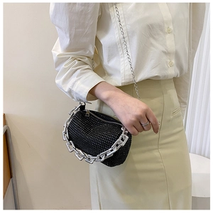 Detail of a black rhinestone cylinder handbag with thick silver chain and metal strap