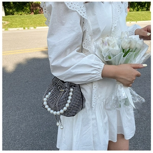 Detail of black rhinestone bucket bag featuring large pearl handle and drawstring closure