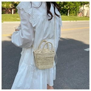 Detail of hand-woven straw bucket bag with drawstring liner shown in outdoor sunlight