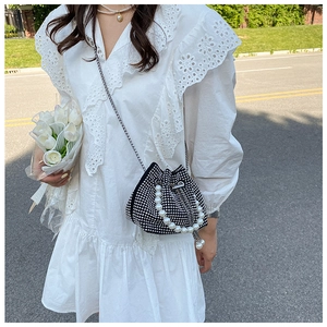 Détail d'un sac seau noir en strass avec poignée en perles et bandoulière chaîne