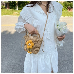 Close-up of handmade straw bucket bag featuring large yellow fabric flower decorations