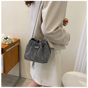 Détail d'un sac seau noir en strass avec bandoulière chaîne argentée sur un modèle
