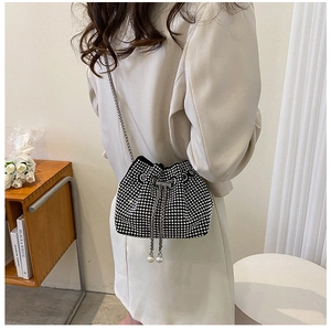 Détail d'un sac seau en strass noirs brillants avec chaîne argentée et cordons perlés