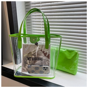 Detail of neon green transparent PVC tote bag with inner pouch and a phone for size reference