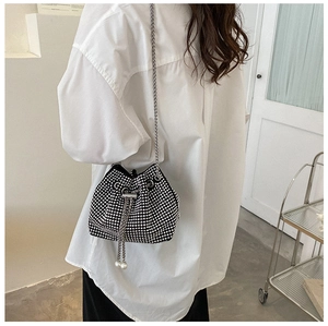 Close-up of black rhinestone bucket bag with silver chain strap and pearl tassel