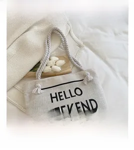 Detail of off-white canvas tote bag with HELLO WEEKEND print and thick cotton rope handles
