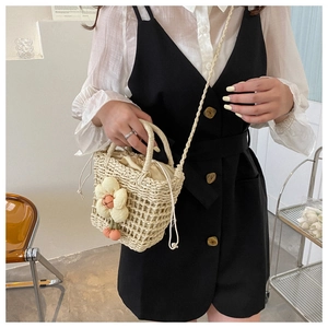 Detail of woven straw bucket bag with floral daisy accents and drawstring inner pouch