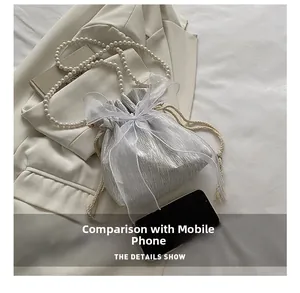 Detailed size comparison of the mini pearl bucket bag with a smartphone and silk bow