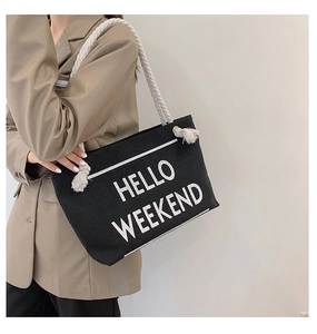 Close-up of black canvas tote bag featuring Hello Weekend print and rope handles