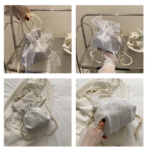 Detail of silver pleated bucket bag with organza bow and pearl handle highlights