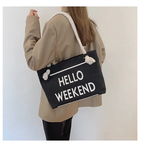 Detail showing high-capacity black canvas tote bag with HELLO WEEKEND text and rope handles
