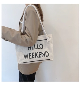 Canvas tote bag with HELLO WEEKEND print and thick rope handles shown on a model