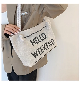 Detail of beige canvas tote bag with black HELLO WEEKEND text and white rope handles