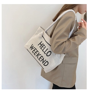 Detail of beige canvas tote bag with HELLO WEEKEND print and rope shoulder straps