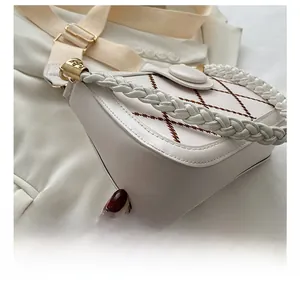 Detail of white leather shoulder bag with brown rhombus stitching and woven handle