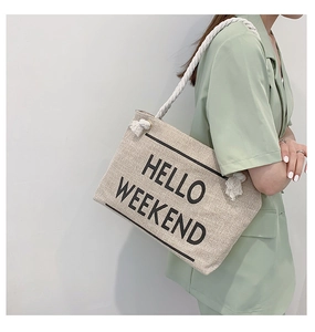 Close-up of beige canvas tote bag with HELLO WEEKEND text and white cotton rope handles
