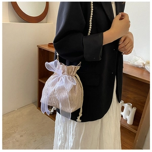 Detail of champagne pleated bucket bag with large organza bow and pearl strap