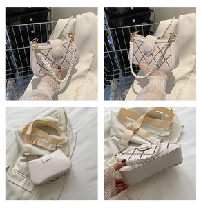 Detail showing white quilted crossbody bag with pearl chain and wide fabric strap