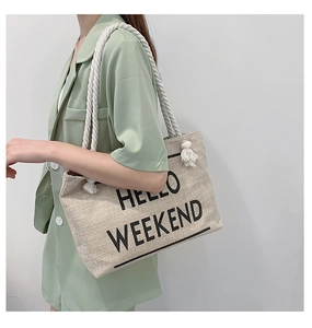 Detail of canvas tote bag with cotton rope handles and HELLO WEEKEND text print