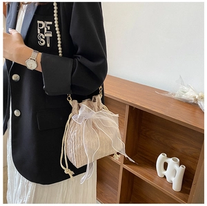 Detail of champagne bucket bag with white organza bow and pearl chain strap