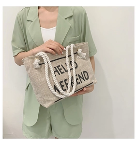 Detail of canvas tote bag with HELLO WEEKEND text and braided cotton rope handles