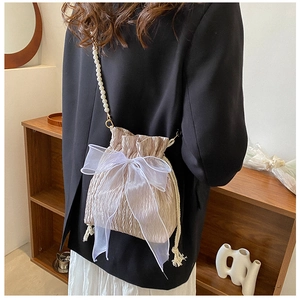 Detail of champagne satin bucket bag with organza bow and pearl shoulder strap