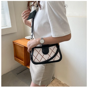Detail of retro quilted crossbody bag with black leather straps and beige fabric texture