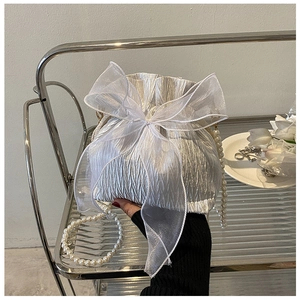Detail of white pleated bucket bag featuring organza bow and pearl bead shoulder strap