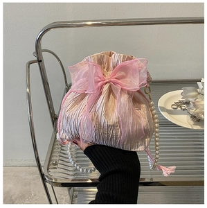 Close-up of pink pleated bucket bag with organza bow and white pearl strap