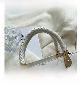 Close-up of a white quilted handbag with a woven handle and elegant gold-tone metal hardware