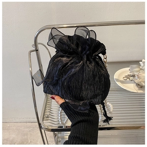 Detail of black pleated bucket bag with organza bow and pearl handle in hand