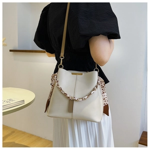 Detail of cream bucket bag with leopard scarf chain handle and sleek leather shoulder strap