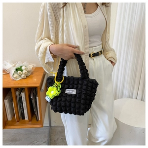 Detail of black pleated bubble shoulder bag with a neon yellow floral bag charm decoration