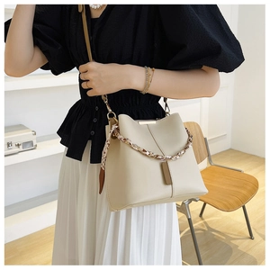 Detail of cream bucket bag featuring gold hardware and leopard print scarf handle