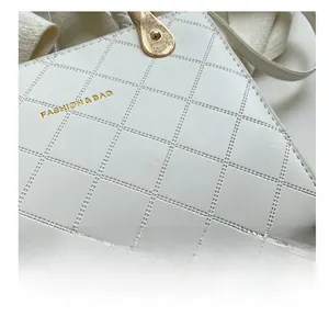 Close-up of white crossbody bag featuring quilted stitching and gold fashion lettering