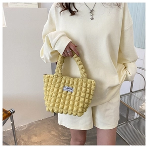 Detailed view of yellow bubble textured fabric and Fashion Instinct label on the handbag