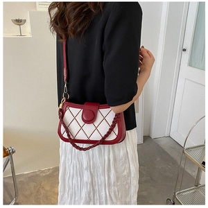 Detail of red leather trim and beige canvas crossbody bag with diamond embroidery
