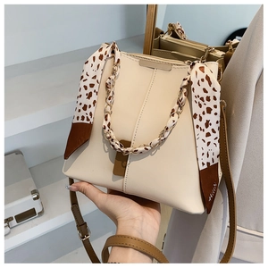 Detail of cream bucket bag with leopard print scarf handle and gold chain detail