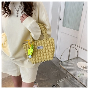 Detail of yellow bubble textured handbag featuring a cute flower charm and fashion label