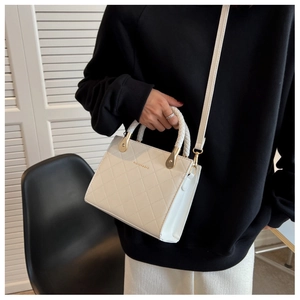 Close-up of quilted white handbag with woven handle and gold hardware detail