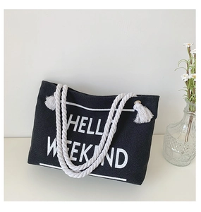 Detail of black canvas tote bag with HELLO WEEKEND print and white rope tassel handle
