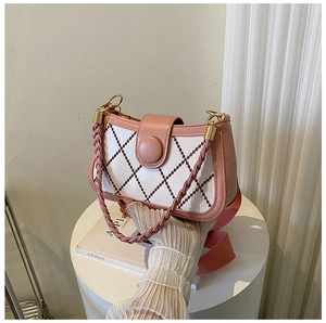 Close-up of pink and white quilted crossbody bag with woven handle on display stand