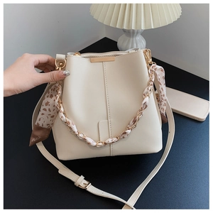 Detail of cream bucket bag with leopard print scarf, gold chain, and fine leather texture