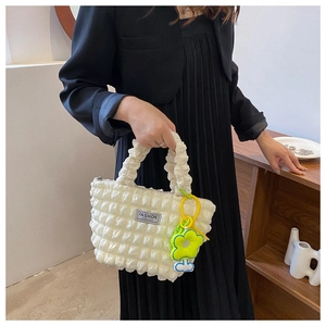 Detail of white bubble texture handbag with fashion tag and yellow flower pendant