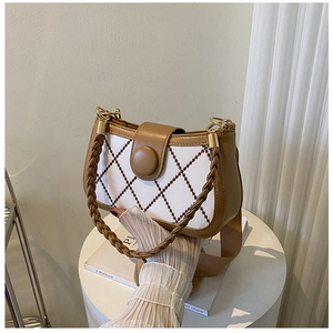 Detailed shot of textured woven handle and geometric embroidery on shoulder bag