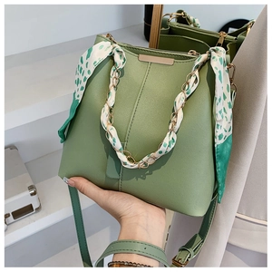 Detail of green bucket bag featuring a silk scarf wrapped chain handle and lychee texture