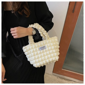 Detailed view of bubble texture fabric and Fashion Instinct label on white handbag