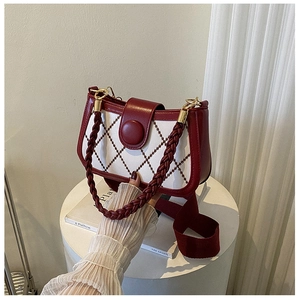 Detail of burgundy leather and beige fabric patchwork crossbody bag with gold hardware