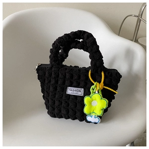 Detailed shot of black bubble texture handbag with neon yellow flower pendant accessory
