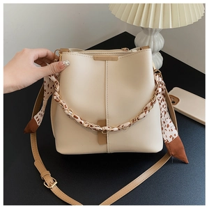 Detail of beige bucket bag featuring gold chain handle wrapped in leopard print scarf